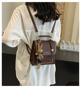 Detalle de la mochila vintage de cuero PU marrón con costuras blancas y colgante de conejo