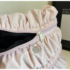 Close-up of pink pleated backpack showing the magnetic buckle and smooth zipper detail