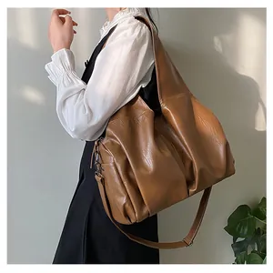 Détail d'un grand sac cabas marron avec bandoulières réglables et texture souple