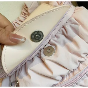 Detail of the magnetic buckle closure on a pink pleated striped nylon backpack