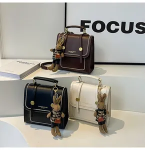 Vista detallada de bolsos vintage con colgantes de conejo y letras doradas de moda