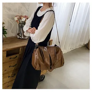 Grand sac cabas en cuir marron avec texture souple et design plissé porté à l'épaule