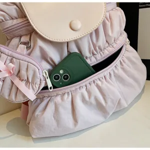 Detail of pink pleated nylon backpack showing multiple zipper pockets and storage depth