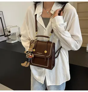 Detalle de mochila vintage de cuero marrón con colgante de conejo y adornos dorados