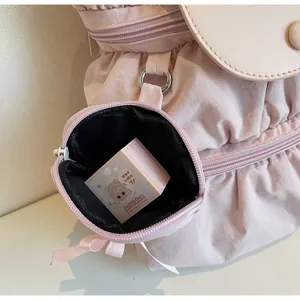 Detail of pink nylon backpack featuring pleated texture and round detachable pouch