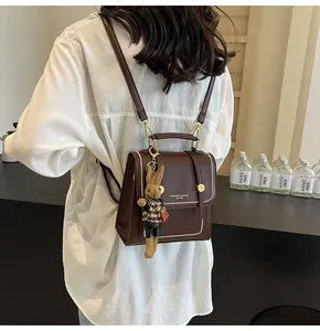 Detalle de mochila vintage marrón oscuro con hebilla dorada y peluche de conejo