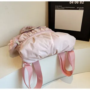 Close-up of pink pleated nylon backpack featuring a soft texture and bow charm detail