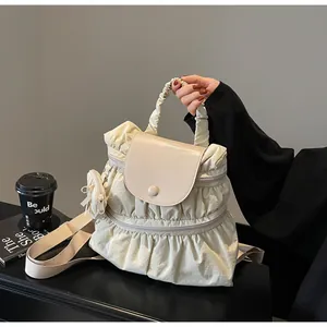 Close-up of cream pleated nylon backpack showing premium texture and mini side pouch