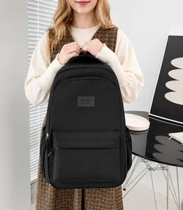 Detail of minimalist black nylon backpack with a sleek square logo and multiple zippers