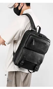 Detail showing the textured black leather texture and zipper pockets of the men's backpack