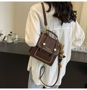 Detalle de bolso retro de cuero marrón con adornos de cuentas blancas y dije de conejo