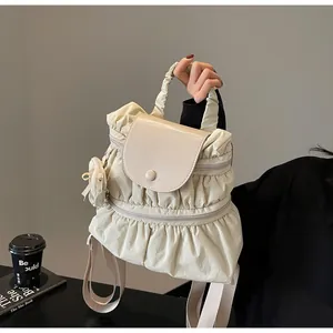 Detail of cream pleated nylon backpack with a mini bow charm and wide straps