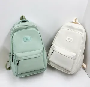 Detail view of lightweight school backpacks in green and beige with large front pocket