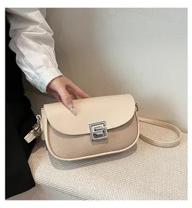 Detail of beige saddle bag featuring smooth leather and fabric patchwork with silver clasp
