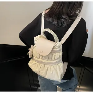 Detail of beige pleated nylon backpack with side pouch accessory on model