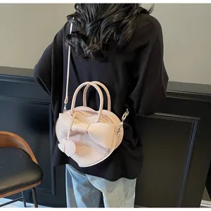 Dettaglio della borsa a mano a forma di cuore rosa chiaro con fiocco e ciondoli