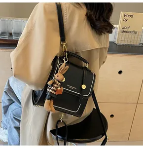 Detalle de la mochila de cuero negro con costuras blancas y colgante de conejo suave