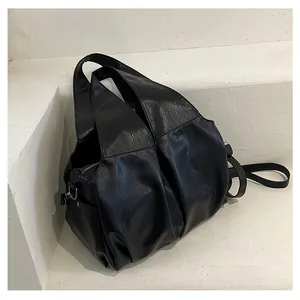 Détail du sac cabas en similicuir noir avec plis texturés et bandoulière réglable