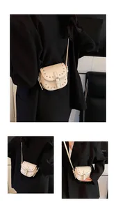 Detail view of cream saddle bag with silver studs and buckle on black blazer