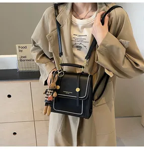 Detalle de bolso bandolera de cuero negro con cuentas blancas y un colgante de conejo peluche