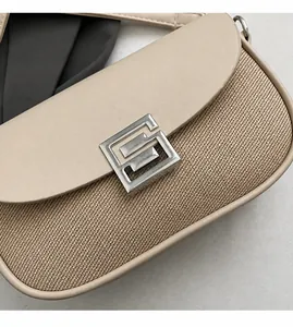 Detail of beige saddle bag showing woven canvas texture and smooth leather flap with silver clasp