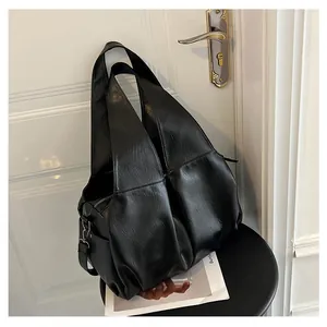 Détail d'un grand sac cabas noir avec texture huilée souple et large bandoulière intégrée