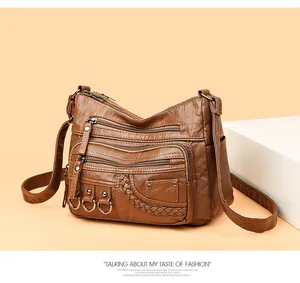 Dettaglio borsa a tracolla in pelle marrone lavata con tasche multiple e zip funzionali