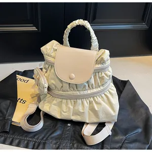 Detail of pleated nylon backpack in cream with round coin pouch on black jacket