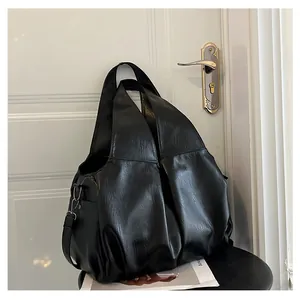 Détail d'un grand sac cabas noir plissé en similicuir lisse avec des bandoulières souples