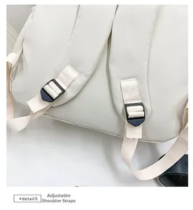 Detail view of adjustable reinforced shoulder straps with black buckles on cream backpack