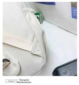 Detailed view of reinforced triangular stitching and side elastic pocket on white backpack