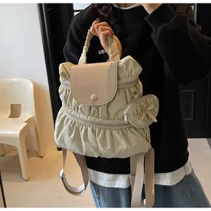 Detail of beige pleated nylon backpack featuring a matching heart-shaped charm and handle