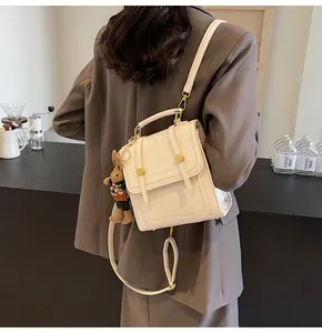 Detalle de la mochila de cuero blanco crema con hebillas doradas y colgante de conejo