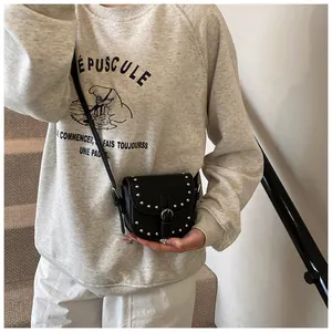 Detail shot of a black mini saddle bag with silver studs on a casual gray sweatshirt
