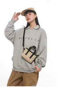 Detail of compact canvas shoulder bag with black strap in a minimalist urban style