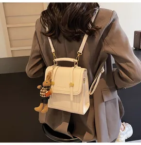 Detalle de la mochila estructurada crema con colgante de conejo y herrajes metálicos dorados
