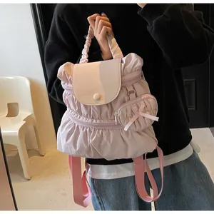 Detail of pink pleated nylon backpack with a heart-shaped charm and silk bow detail