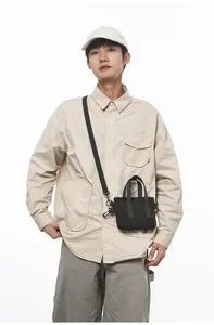 Minimalist black canvas shoulder bag shown as a crossbody on a studio model