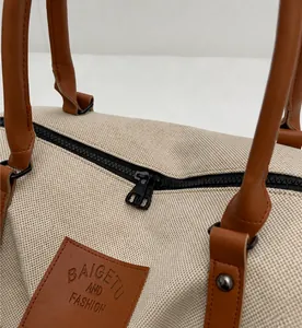 Detailed close-up of smooth black resin zipper and brown leather trim on canvas travel bag