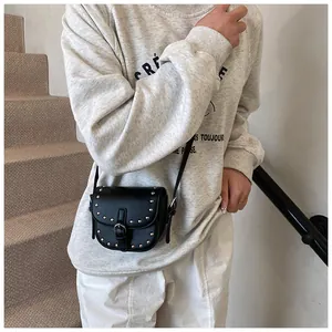 Detail view of mini black PU saddle bag with silver studs on gray casual outfit