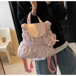 Detail of pink pleated nylon backpack with a decorative mini bow pouch charm