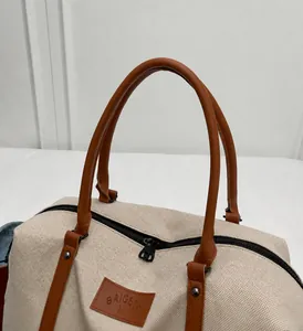 Close-up of durable leather handles and branded patch on large canvas travel bag
