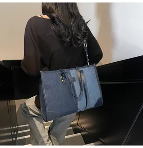 Dettaglio della borsa tote in denim con patchwork bicolore e cuciture bianche a contrasto