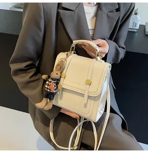 Detalle de la mochila convertible de cuero crema con hebillas doradas y colgante de conejo