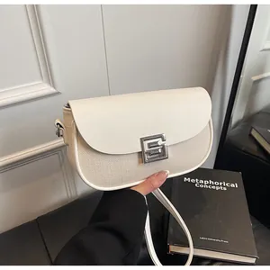 Detail of minimalist saddle bag featuring cream leather, canvas texture, and silver clasp