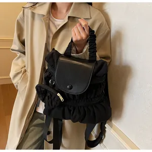 Detail of ruffled handle and detachable mini coin purse on a black nylon backpack