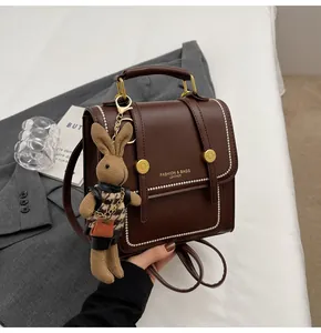 Detalle de bolso de cuero PU marrón oscuro con herrajes dorados y colgante de conejo