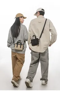 Mini canvas tote bags in khaki and black with adjustable shoulder straps on two models