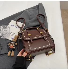 Detalle de bolso vintage marrón con asa metálica y costuras de perlas sobre una chaqueta