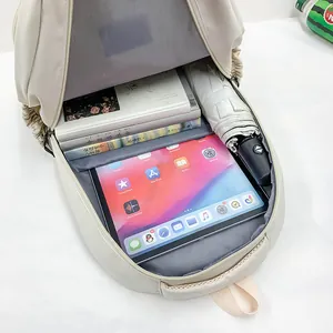 Minimalist beige backpack with large capacity showing interior storage for books and tablet